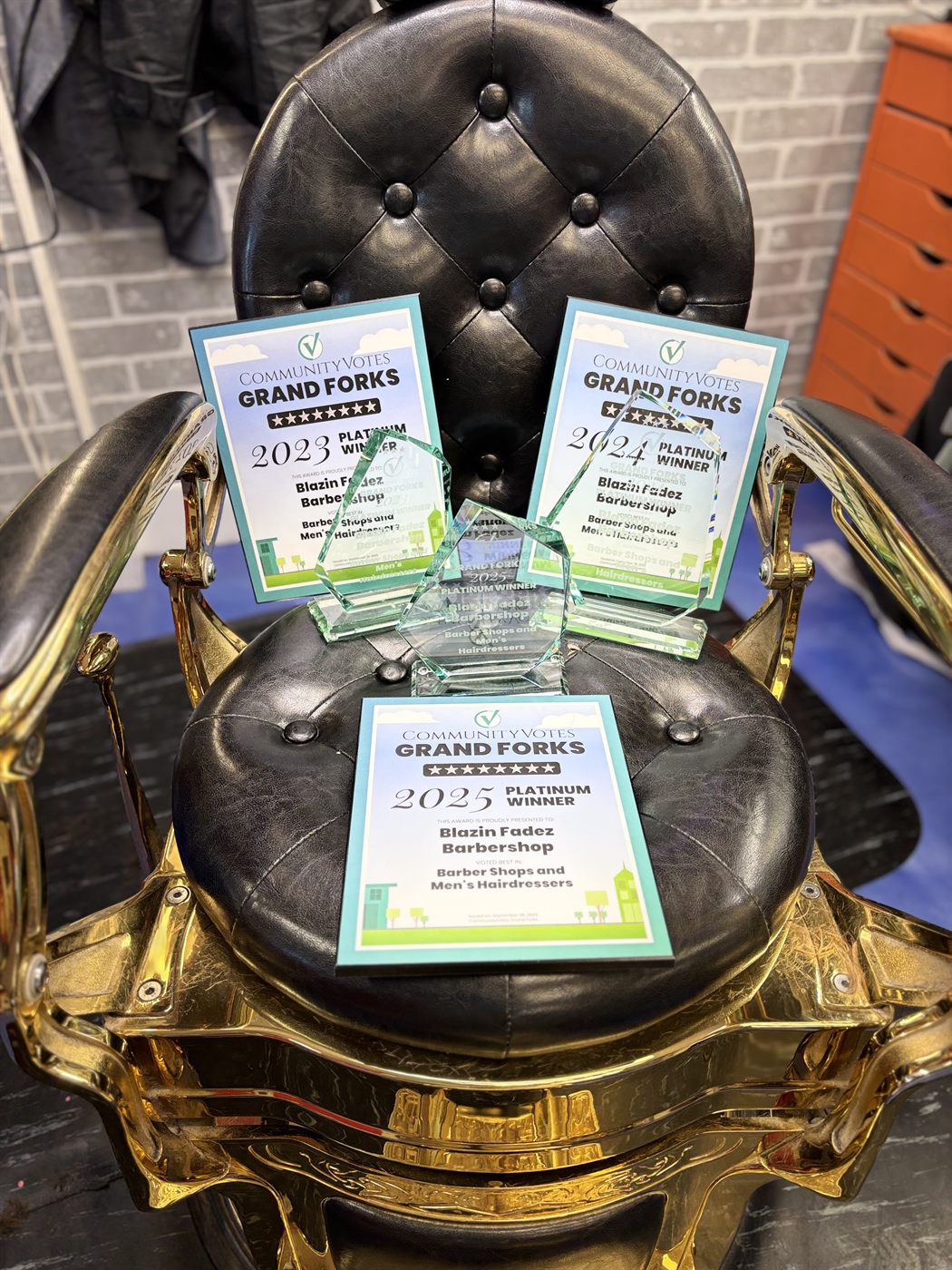 Community Votes 3× Platinum Winner trophies on gold barber chair